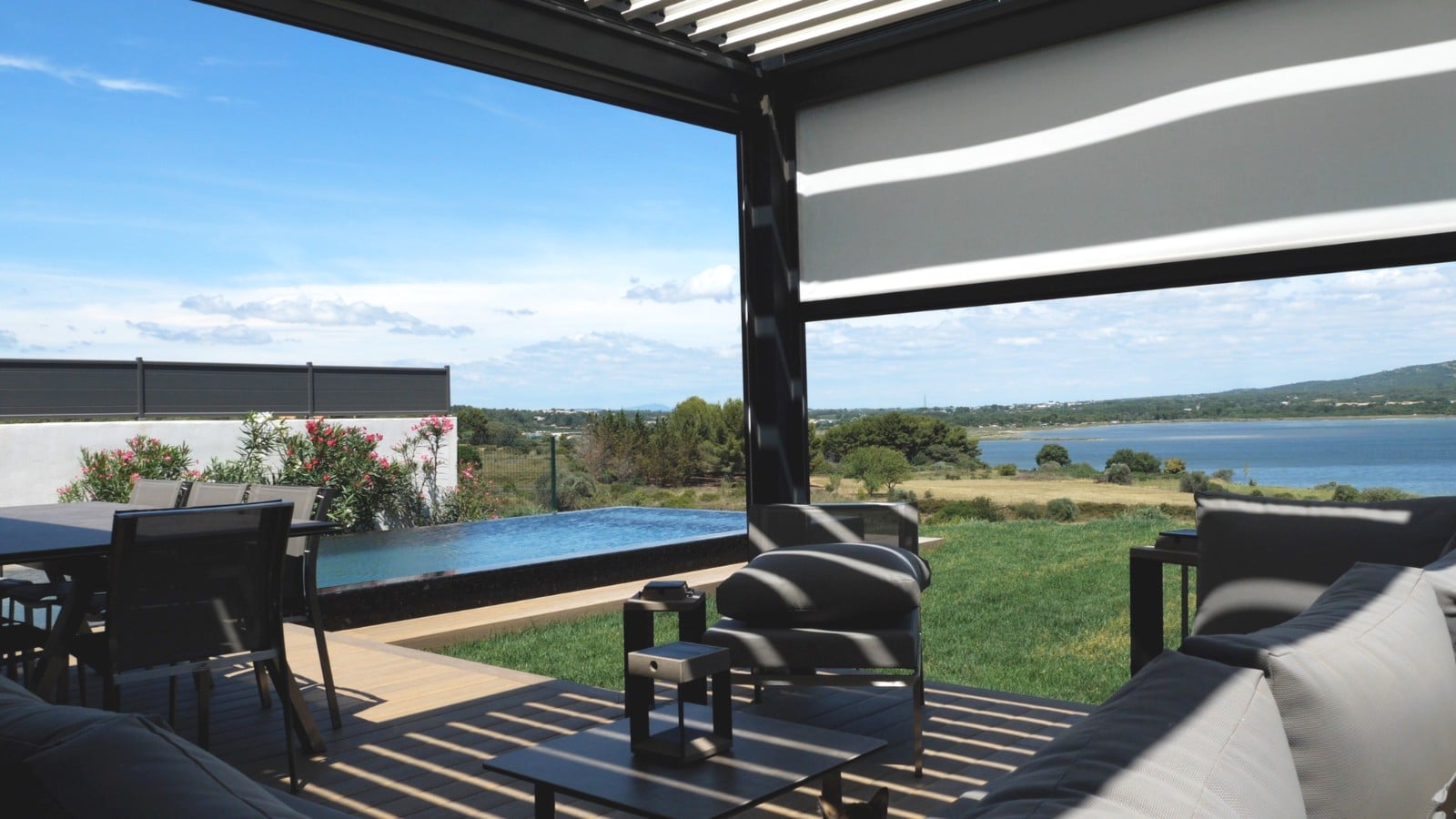 Vu d'une terrasse sur l'étang de thau avec en premier plan une pergola bioclimatique et un store vertical pour se protéger du soleil